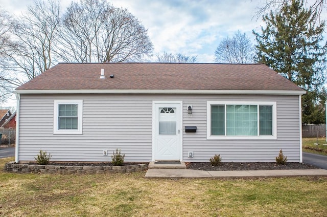 view of front of property featuring a front lawn and roof with shingles