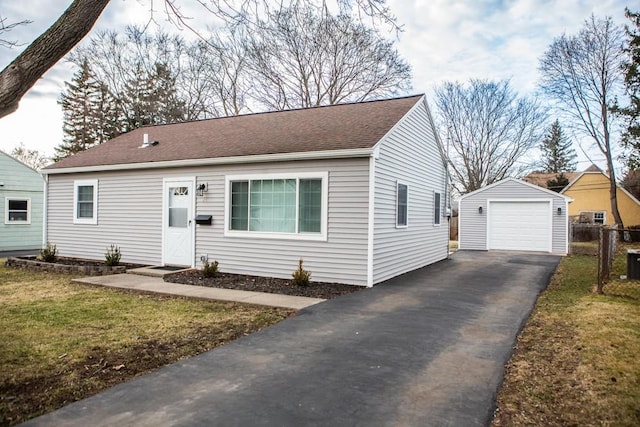 view of front of house with a detached garage, a front lawn, aphalt driveway, roof with shingles, and an outdoor structure