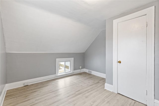 additional living space featuring visible vents, baseboards, wood finished floors, and vaulted ceiling