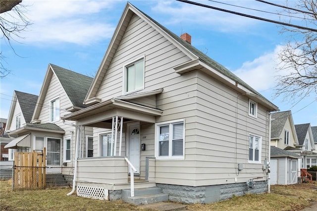 view of front of home featuring a shingled roof, a chimney, and fence