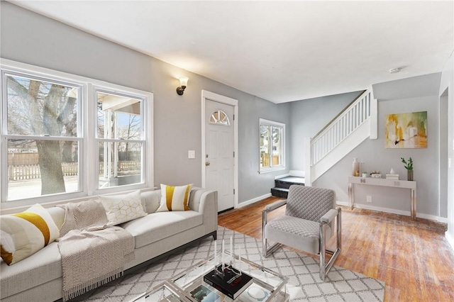 living room featuring stairway, baseboards, and light wood-style floors