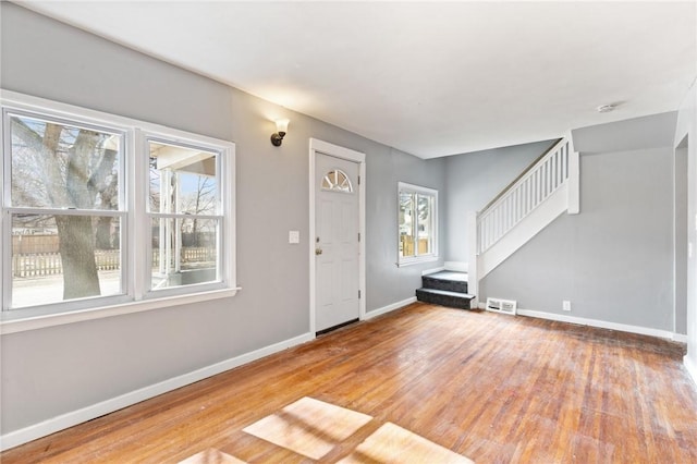 foyer with stairs, visible vents, baseboards, and hardwood / wood-style floors