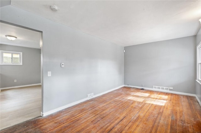 unfurnished room with wood finished floors, visible vents, and baseboards