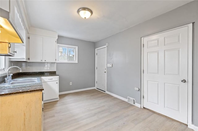 kitchen with visible vents, white cabinetry, baseboards, and a sink