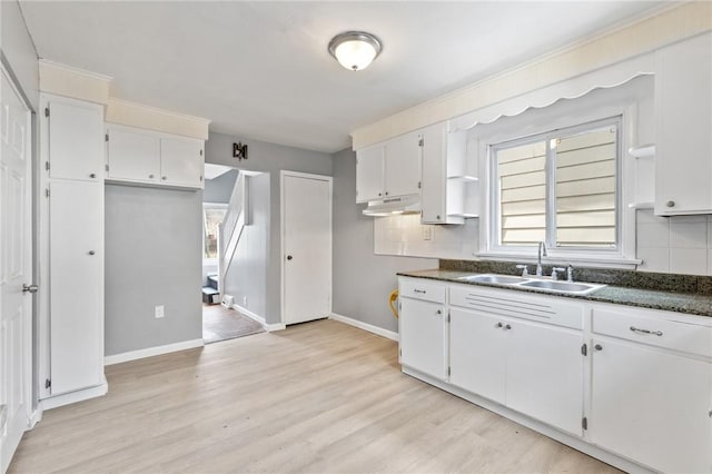 kitchen with a sink, dark countertops, white cabinets, and light wood finished floors