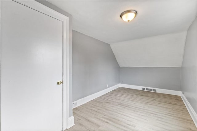 additional living space with vaulted ceiling, visible vents, baseboards, and wood finished floors