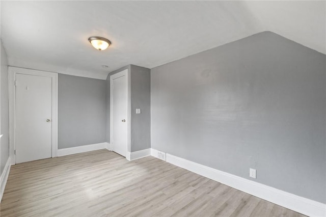 unfurnished bedroom with vaulted ceiling, wood finished floors, baseboards, and a closet