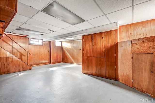 basement with wooden walls and a paneled ceiling