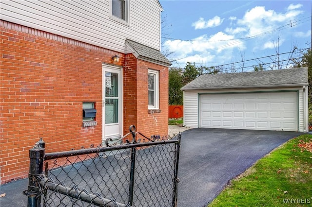 view of home's exterior with a detached garage, fence, an outdoor structure, a shingled roof, and brick siding