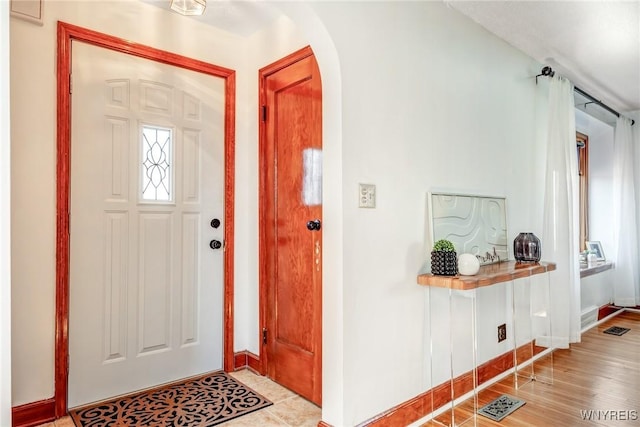 entryway with visible vents, wood finished floors, arched walkways, and baseboards