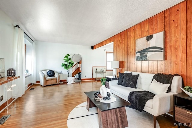 living area with stairway, visible vents, wood walls, and light wood-type flooring