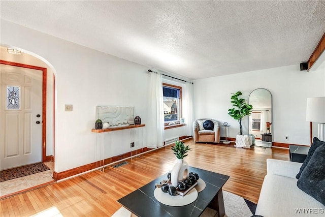 living room with visible vents, arched walkways, a textured ceiling, and wood finished floors