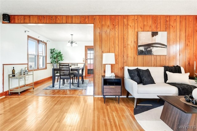 living room with a notable chandelier, light wood-type flooring, and baseboards