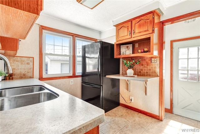 kitchen with a sink, light tile patterned floors, light countertops, and freestanding refrigerator