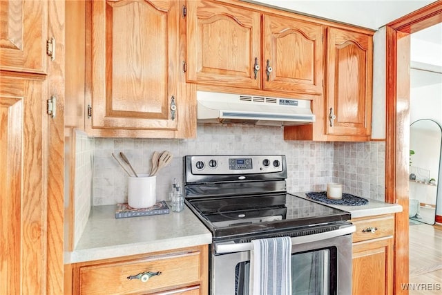 kitchen with decorative backsplash, light countertops, stainless steel electric stove, and under cabinet range hood