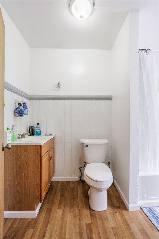 bathroom with vanity, a shower with curtain, wood finished floors, wainscoting, and toilet