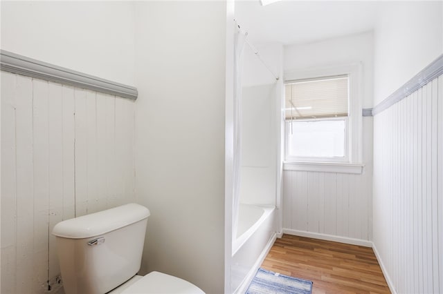 full bathroom featuring wood finished floors, baseboards, toilet, walk in shower, and a bath