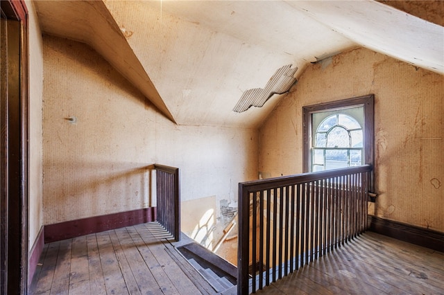 additional living space featuring vaulted ceiling, hardwood / wood-style flooring, and baseboards