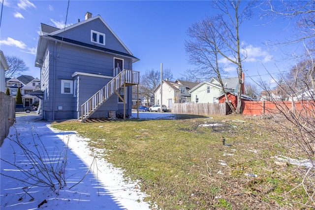 back of house featuring a yard, a residential view, stairs, and fence