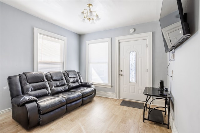 living area featuring a chandelier, baseboards, and light wood-style flooring