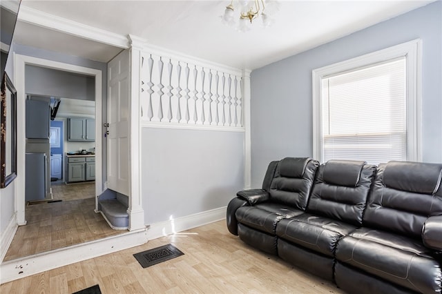 living area with visible vents, baseboards, an inviting chandelier, and wood finished floors