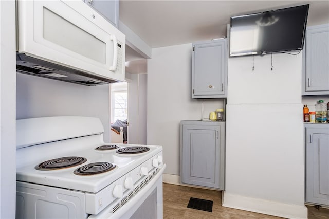 kitchen featuring white appliances, light wood-style flooring, and gray cabinets