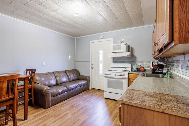 kitchen featuring a sink, tasteful backsplash, white appliances, crown molding, and light wood finished floors