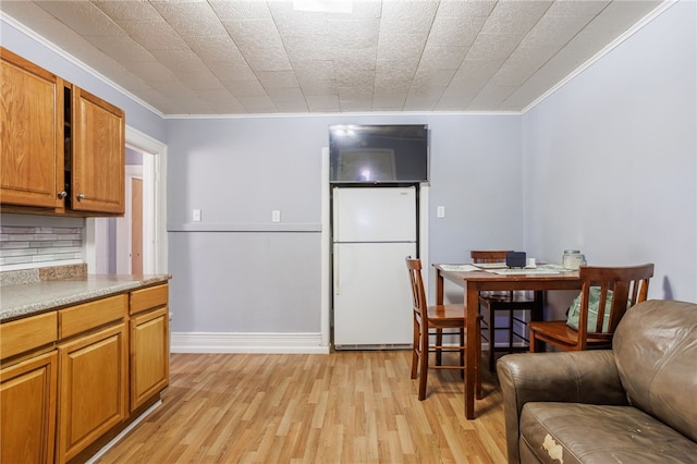 kitchen with light wood finished floors, brown cabinets, freestanding refrigerator, and ornamental molding