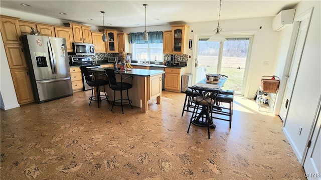 kitchen with a kitchen bar, decorative backsplash, a wall mounted AC, stainless steel appliances, and glass insert cabinets