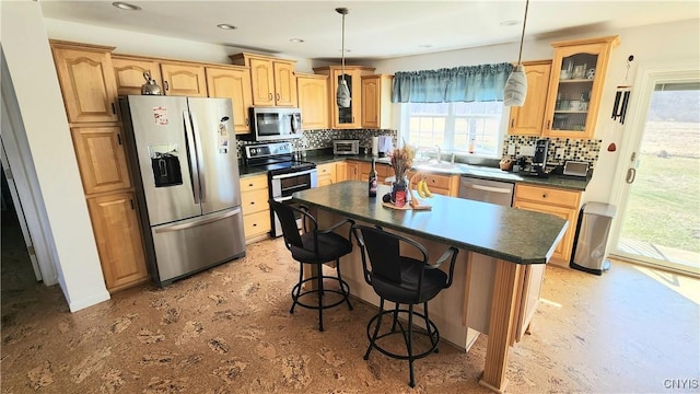 kitchen with dark countertops, decorative backsplash, appliances with stainless steel finishes, and glass insert cabinets