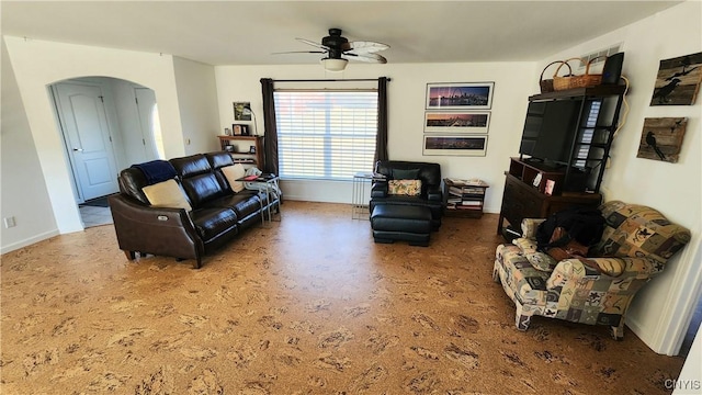 living area featuring baseboards, arched walkways, and ceiling fan