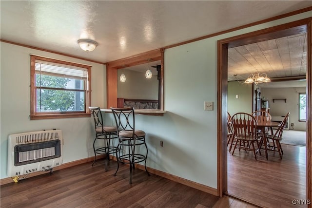 dining area featuring heating unit, wood finished floors, baseboards, and ornamental molding