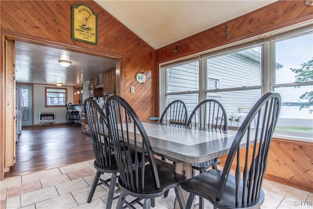 dining space with lofted ceiling, wooden walls, heating unit, and light tile patterned floors