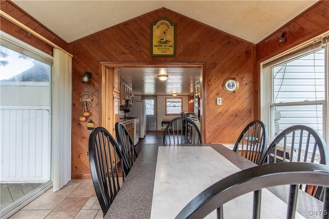 dining room with lofted ceiling, light tile patterned floors, heating unit, and wood walls