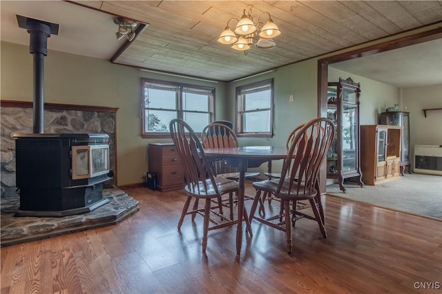 dining space featuring wood finished floors, wooden ceiling, and a wood stove