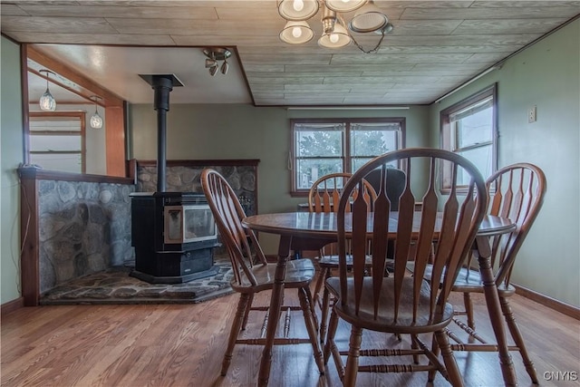 dining area featuring baseboards, wood finished floors, and a wood stove