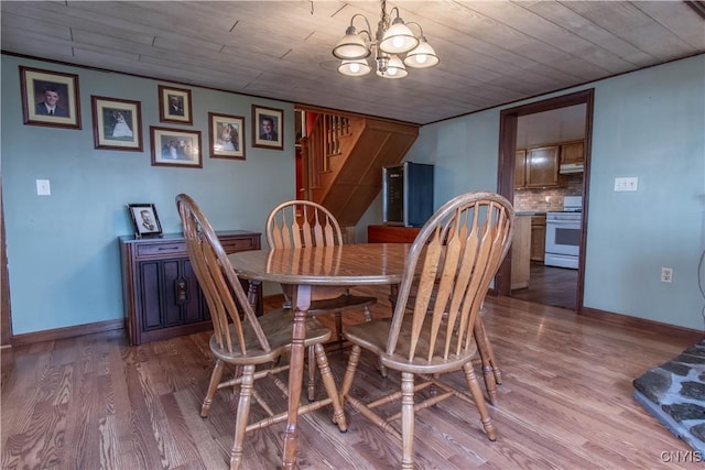 dining room with stairs, an inviting chandelier, wood finished floors, and baseboards