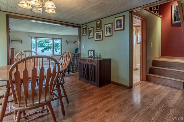 dining room featuring stairs, a notable chandelier, wood finished floors, and baseboards