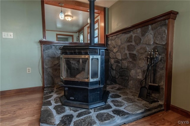 interior details featuring a wood stove, wood finished floors, and baseboards