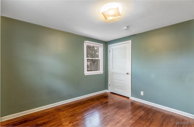 spare room featuring baseboards and wood finished floors