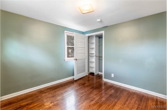 unfurnished bedroom with wood finished floors, baseboards, and a closet