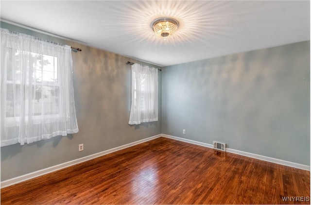 unfurnished room with visible vents, baseboards, and wood finished floors