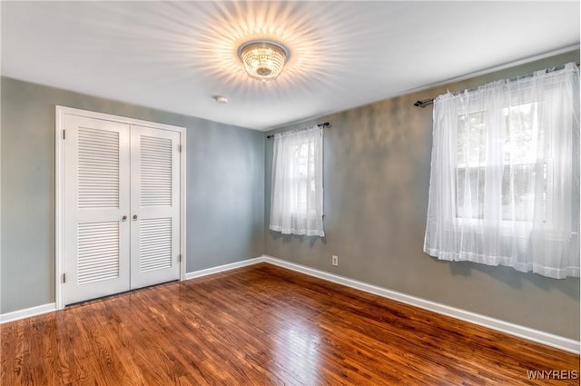 unfurnished bedroom featuring wood finished floors, a closet, and baseboards