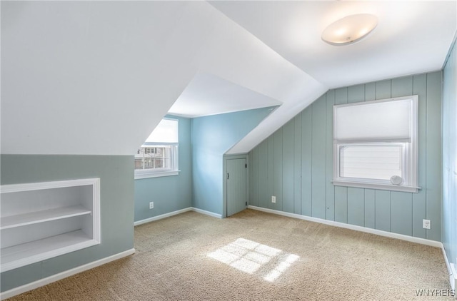 bonus room with vaulted ceiling, built in shelves, baseboards, and carpet floors