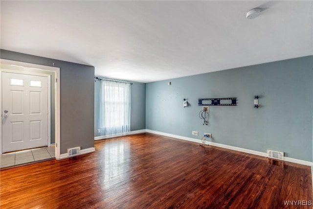 unfurnished living room with visible vents, baseboards, and wood finished floors