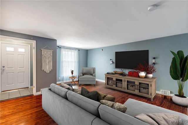 living room with wood finished floors, visible vents, and baseboards