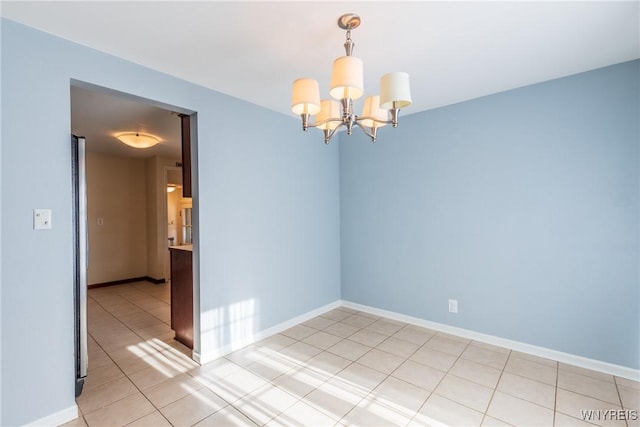 empty room with light tile patterned flooring, baseboards, and a chandelier