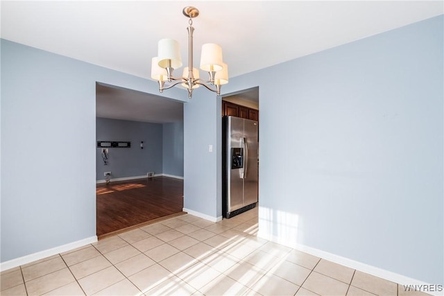 spare room featuring a chandelier, baseboards, and light tile patterned flooring