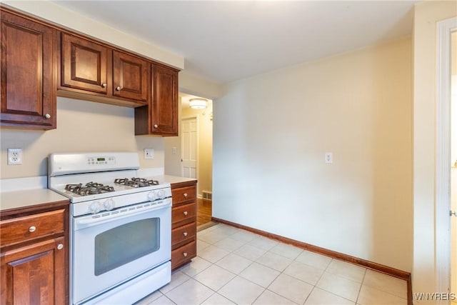 kitchen featuring visible vents, light countertops, baseboards, and white gas range oven