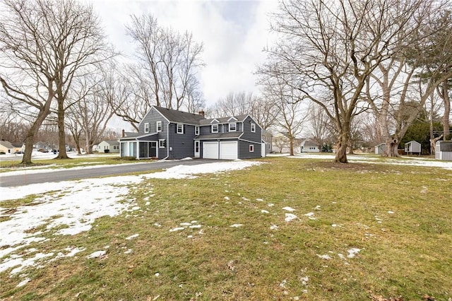 view of front facade with aphalt driveway, a front lawn, a chimney, and an attached garage